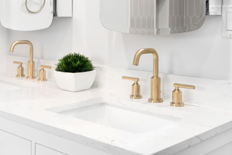 A bathroom detail with gold faucets, white vanity cabinet