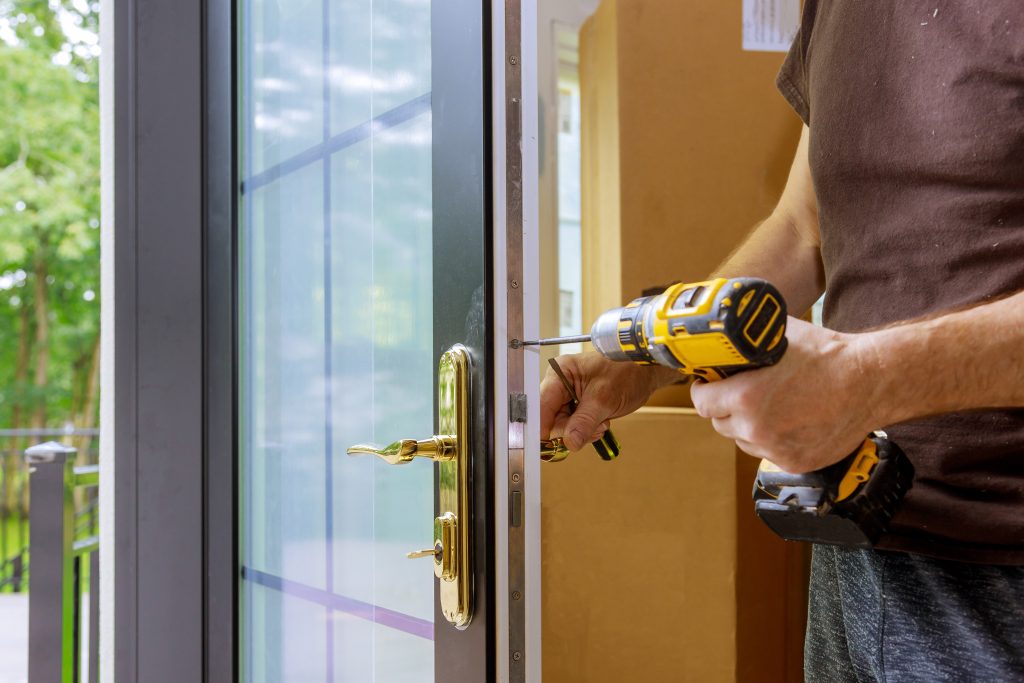 front door hardware Install the door handle with a lock, Carpenter tighten the screw, using an electric drill screwdriver, close-up.